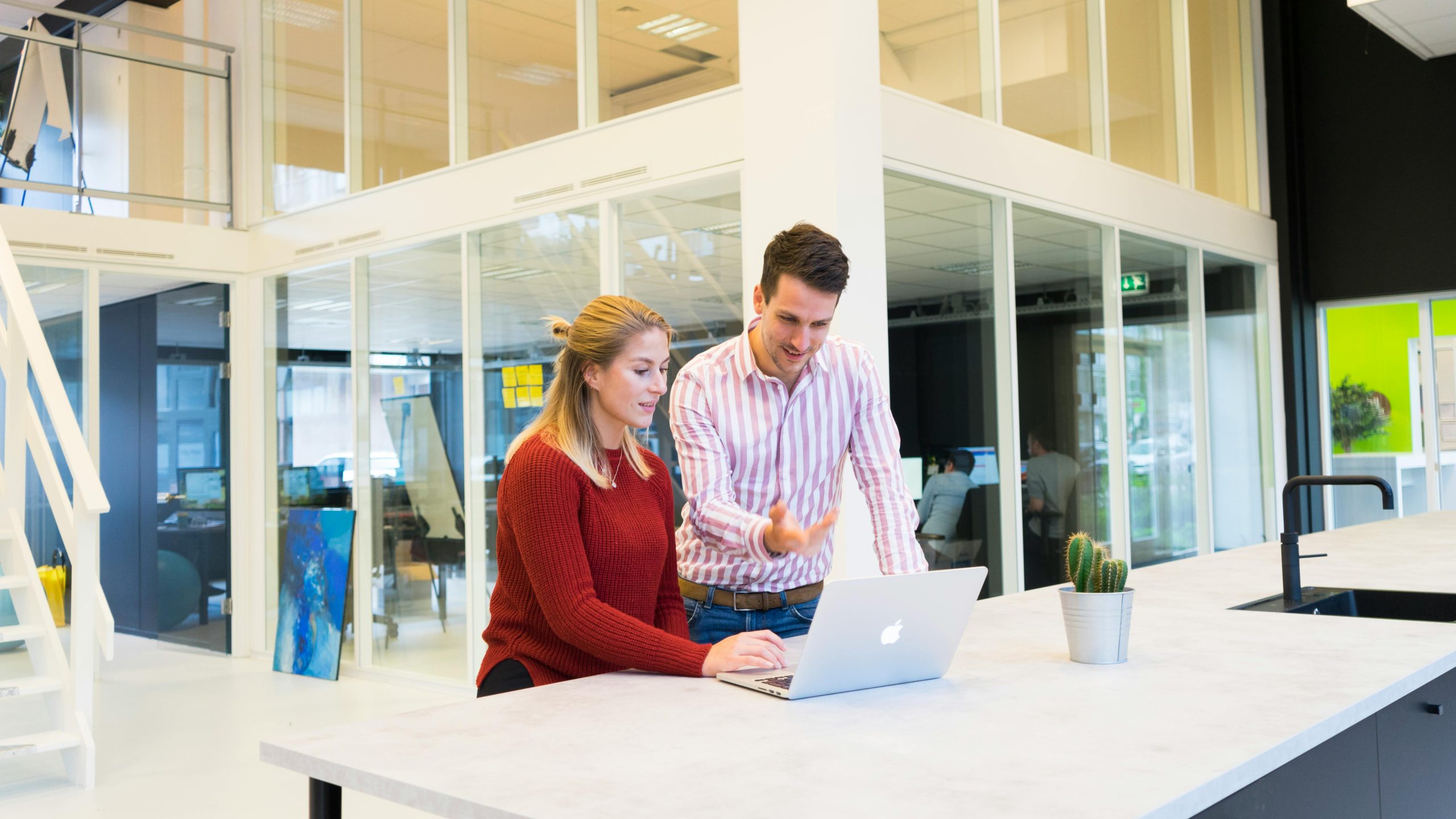 IT support technician helping a colleague at a laptop